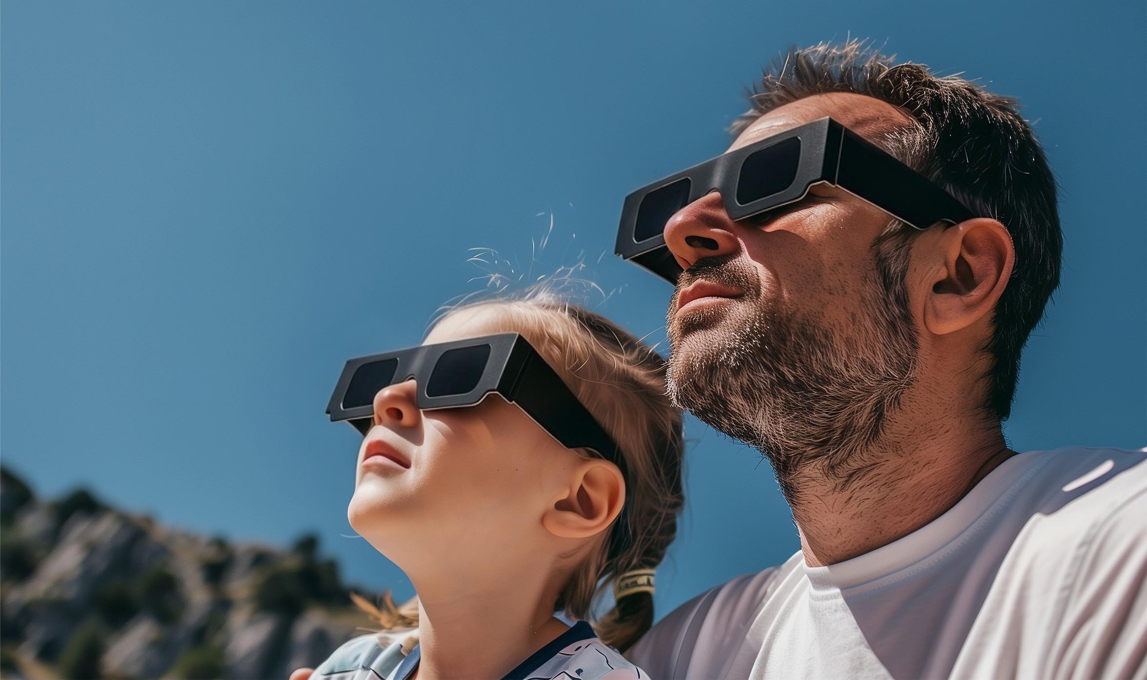 Padre e hija observando el cielo con gafas solares.