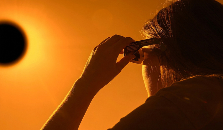 Woman is looking on solar eclipse through three sunglasses. Sun eclipse concept.