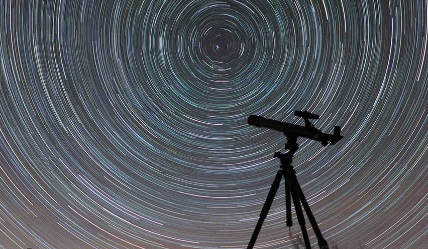 Infografía de un cielo estrellado con un telescopio observando un eclipse.