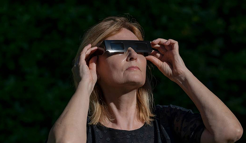 Una mujer observa un eclipse usando unas gafas protectoras.