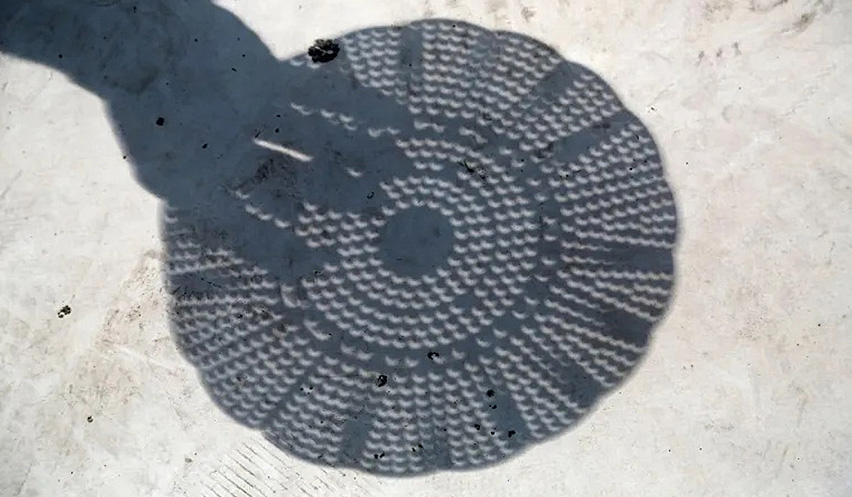 Sombra proyectada en el suelo de una espumadera para eclipses.