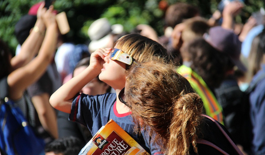 Grupo de niños observando un eclipse con gafas protectoras.